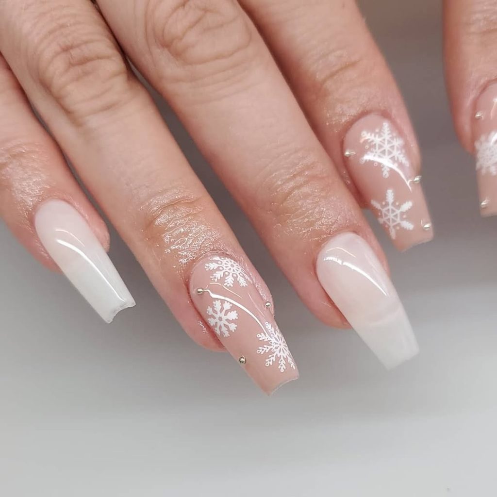Coffin nude nails with white snowflake nail art on accent nails