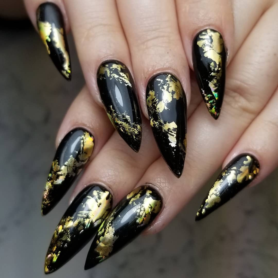 Black stiletto nails with gold foil flake accents