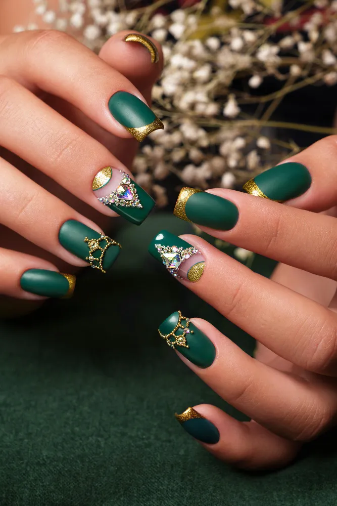 Short square matte deep green nails with gold glitter French tips and jewel accents