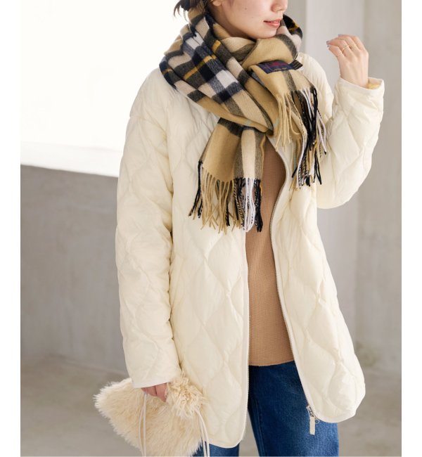 Woman in a cream quilted jacket, camel check scarf, tan top and blue jeans