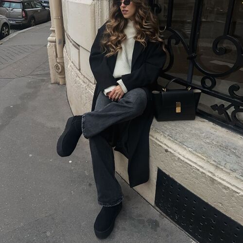Woman in wide-leg jeans, black ankle boots and a long coat