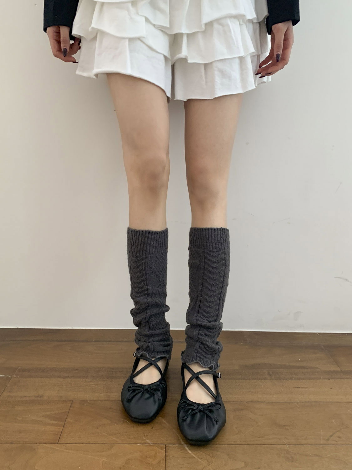 Light grey ribbed leg warmers over black opaque tights with a black denim mini skirt and fuzzy black boots