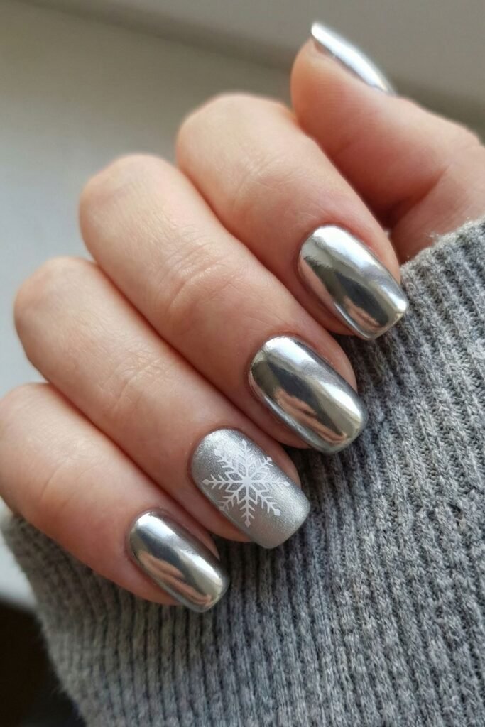 Silver mirror-chrome nails with a white snowflake accent