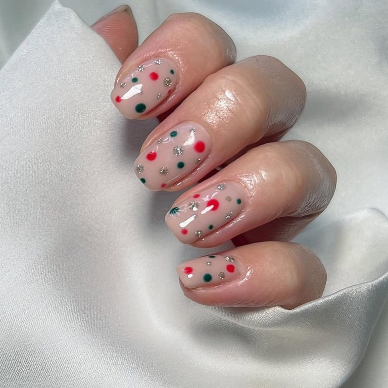 Short oval sheer-nude nails with red and green confetti dots and silver micro-glitter