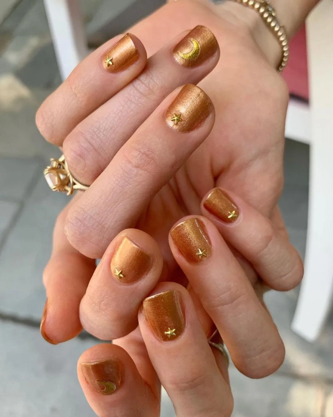 Short squoval nails in copper metallic with tiny gold star studs and a crescent moon accent