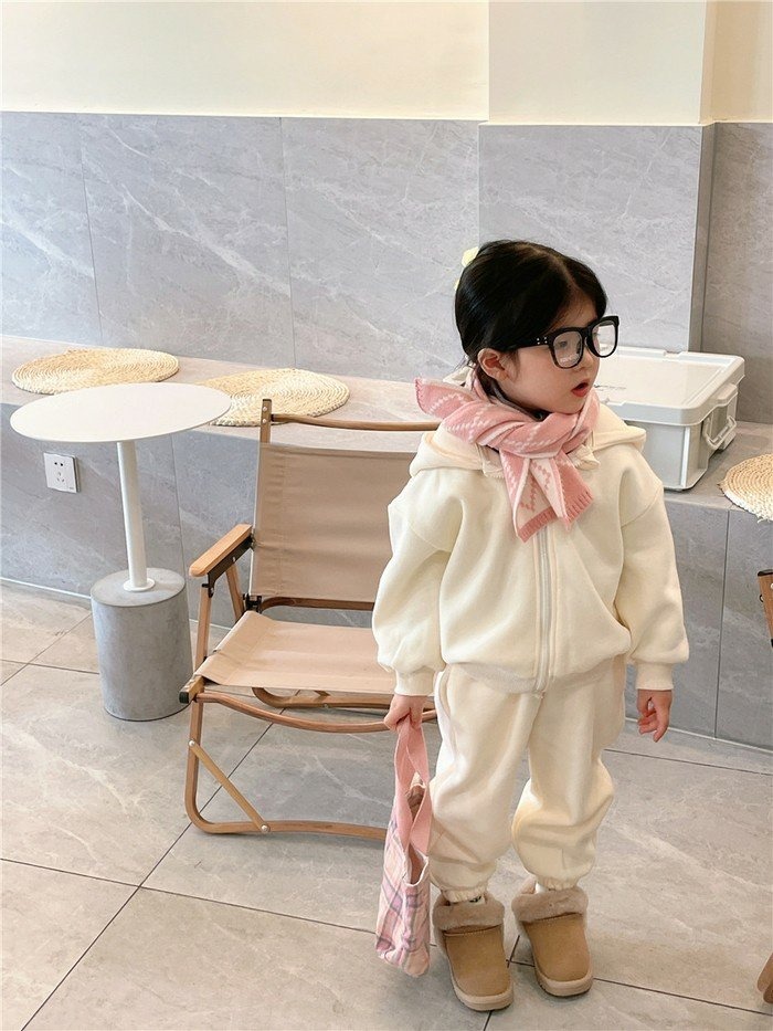 A toddler girl wearing a cream fleece hoodie set with a pink scarf and tan slipper boots
