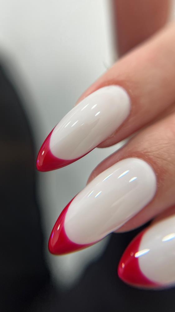 Long almond nails with a milky white base and cherry red french tips