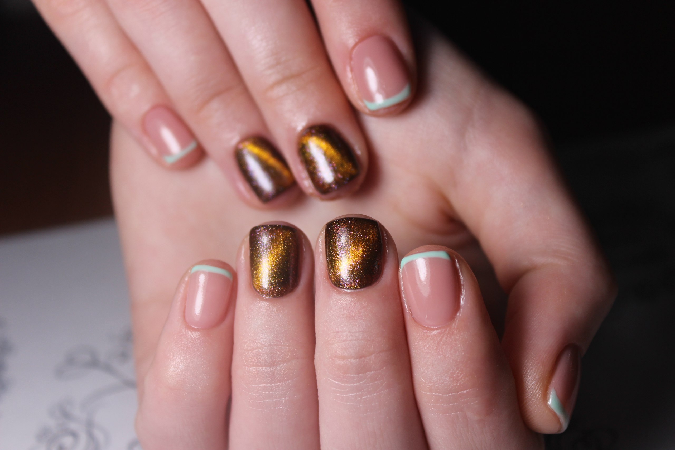 Bronze cat-eye magnetic accent nails paired with nude nails with mint micro-French tips