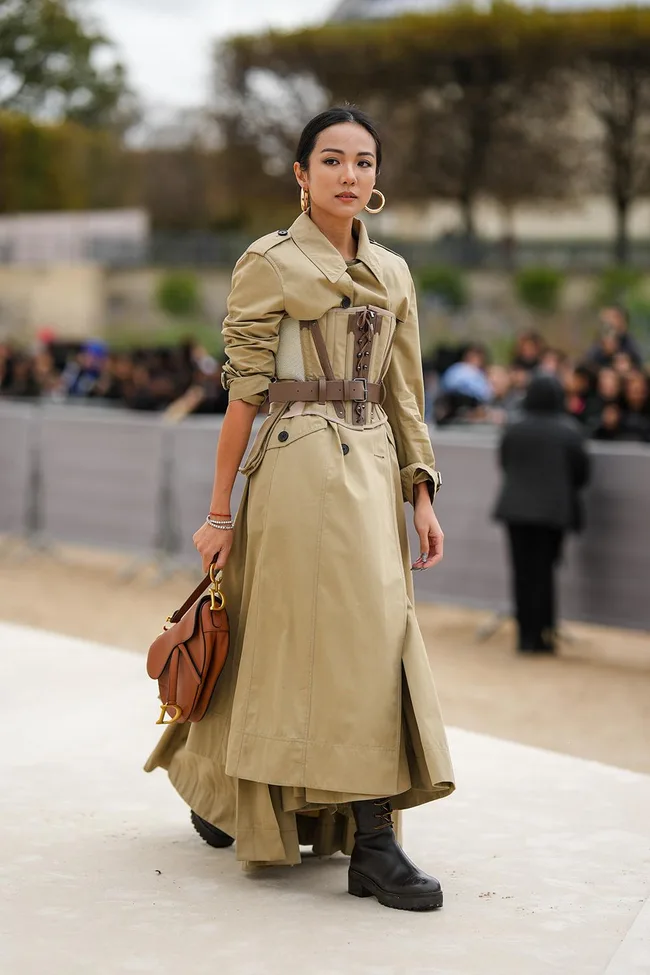 Woman at Paris Fashion Week in a belted beige trench coat with a corset-style belt and black platform combat boots