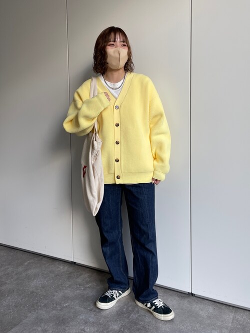 Woman in a pale-yellow oversized cardigan, white tee, dark wide-leg jeans and black-and-white sneakers