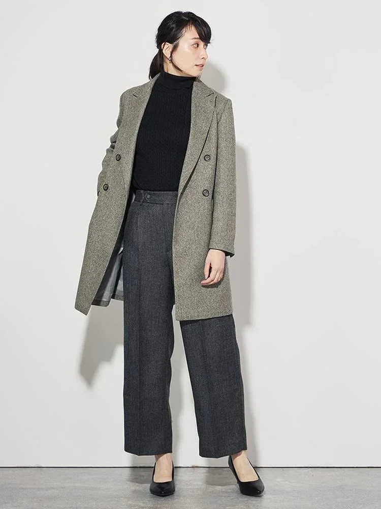 Woman in a black turtleneck, gray tailored trousers and a long coat