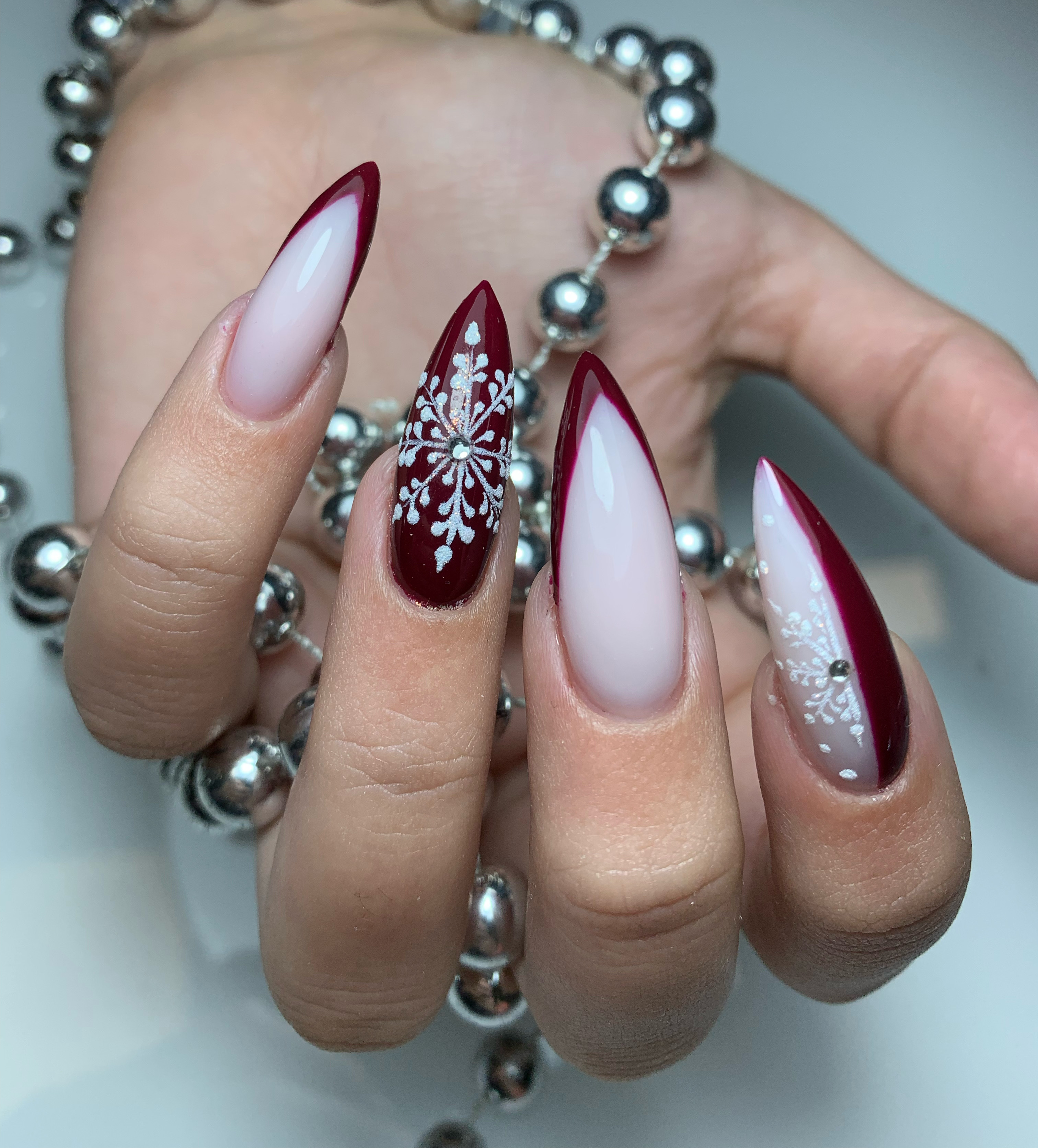 Red and pale pink split stiletto nails with white snowflake and rhinestone accent