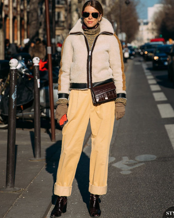 Woman in a cream sherpa fleece jacket with tan corduroy pants and brown boots