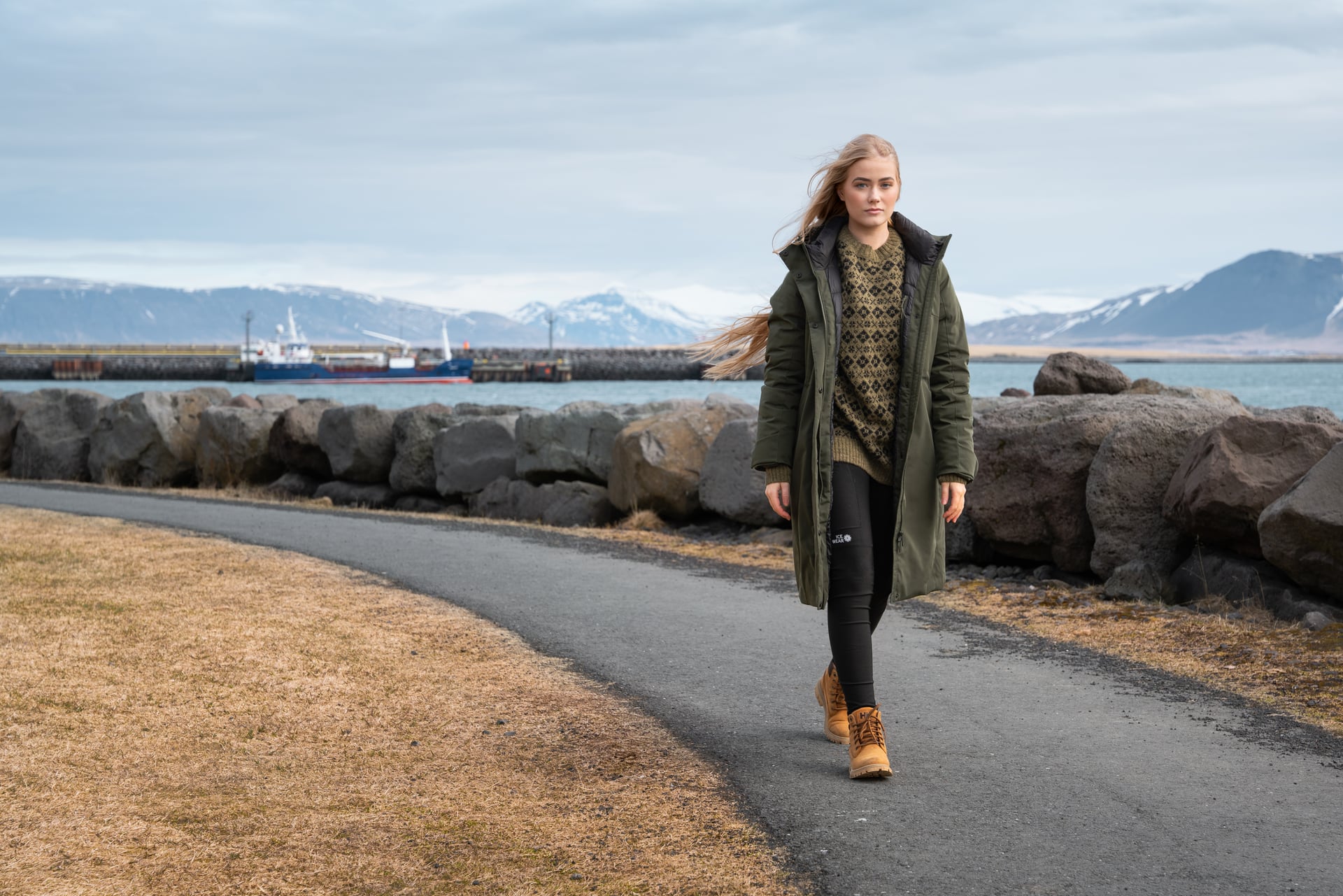 Woman wearing a fur-hood parka over a green wool sweater in an Iceland winter landscape