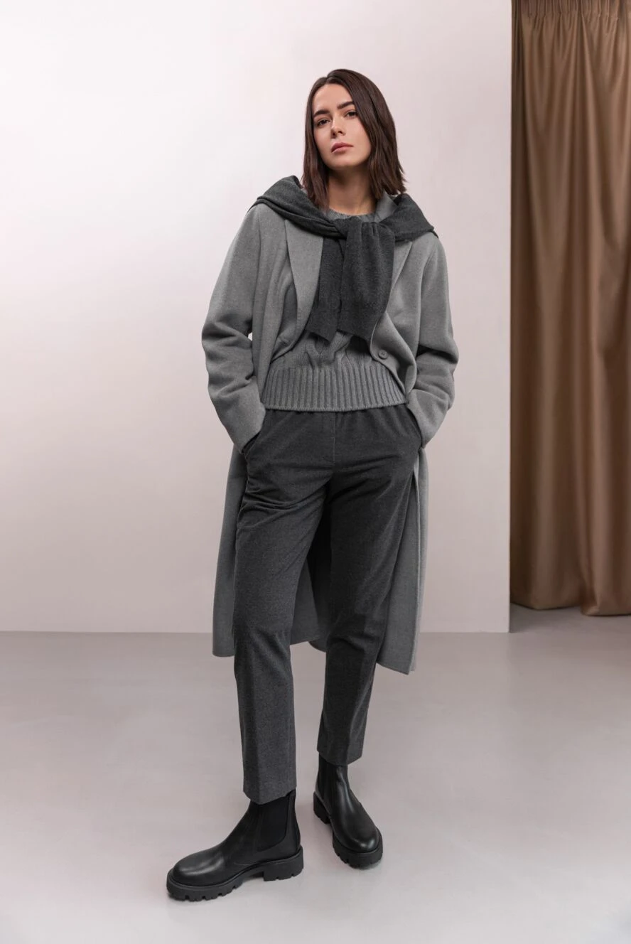 Woman in a tonal grey outfit with long coat, scarf, trousers and black Chelsea boots