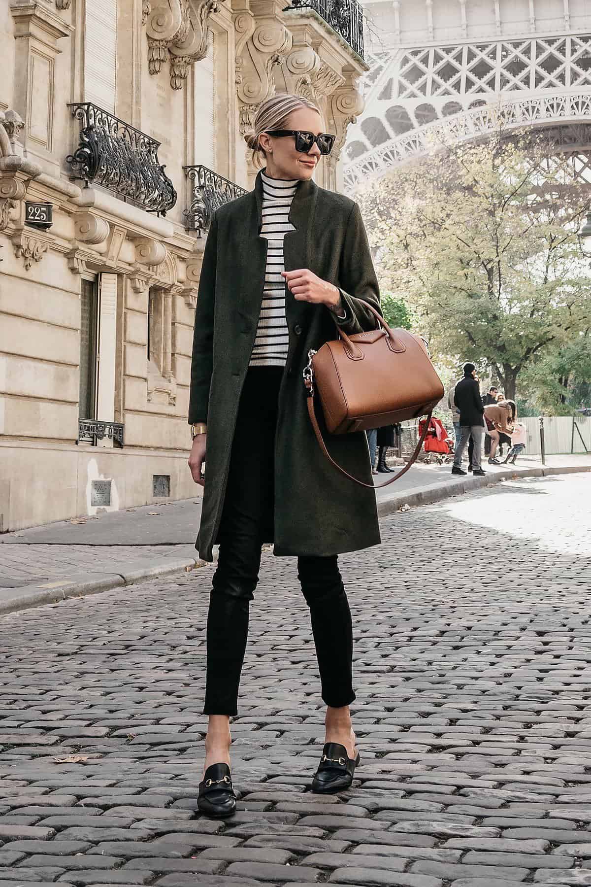Woman in Paris wearing a black trench coat over a striped turtleneck with black pants and loafers