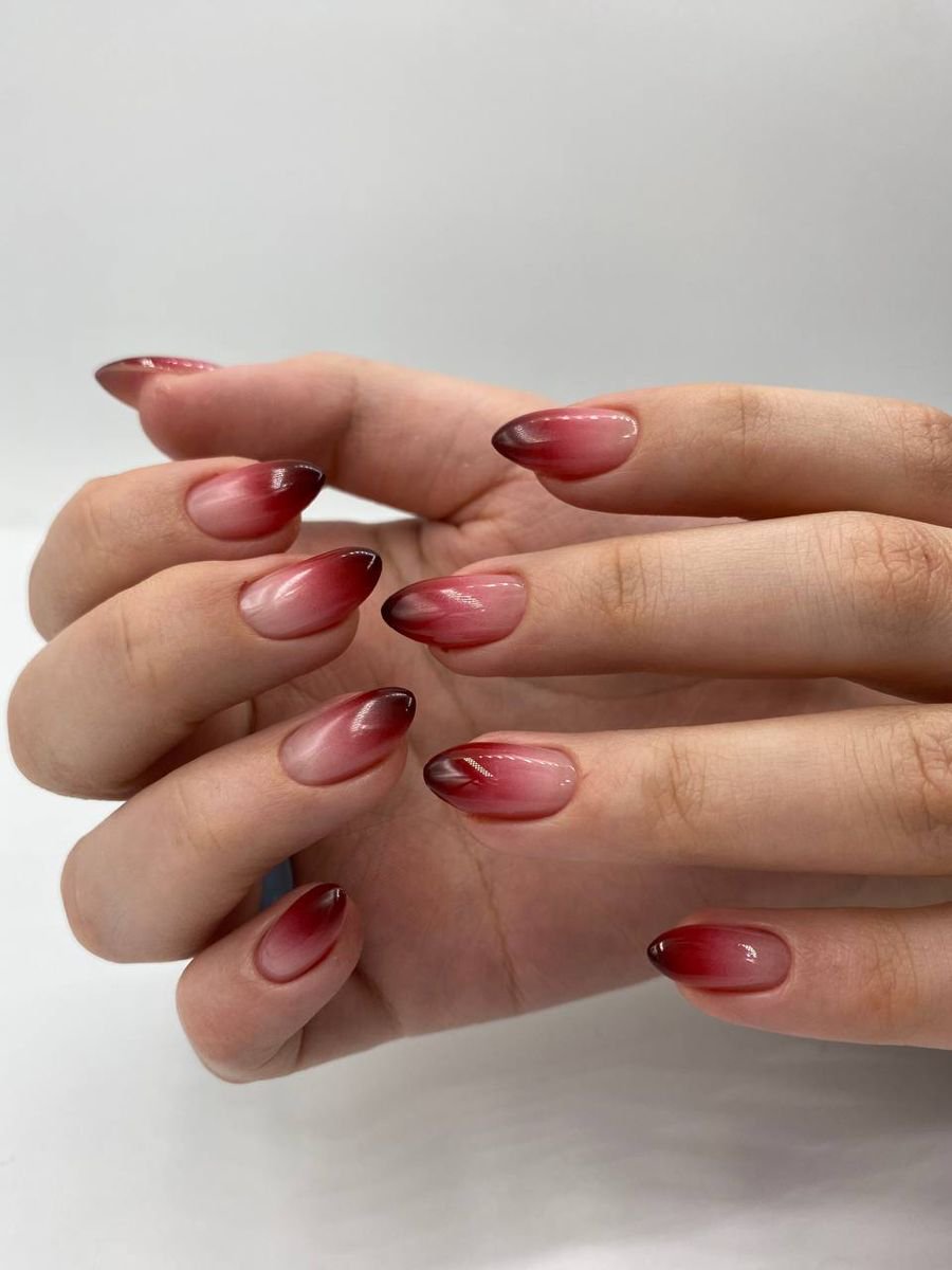 Cherry red ombré nails fading from dark tips to a nude base