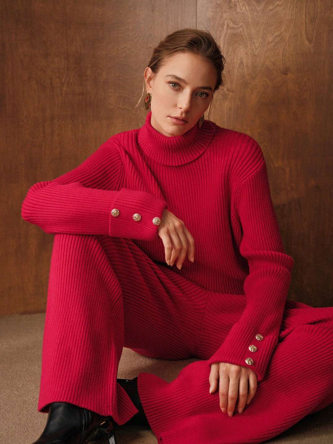 Woman wearing a red ribbed knit two-piece set with a turtleneck sweater and wide-leg knit trousers
