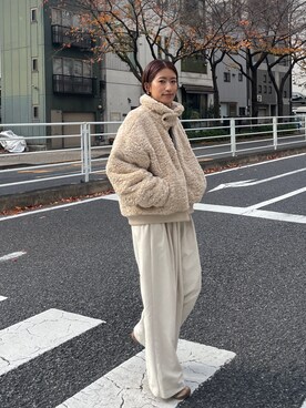 Woman in a beige teddy blouson jacket with cream wide-leg trousers