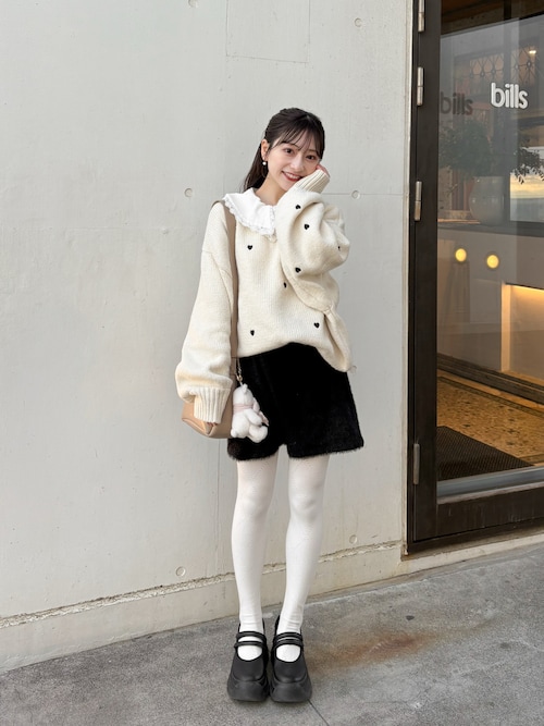 Woman in a chunky knit sweater with a skirt and tights, paired with Mary Jane shoes