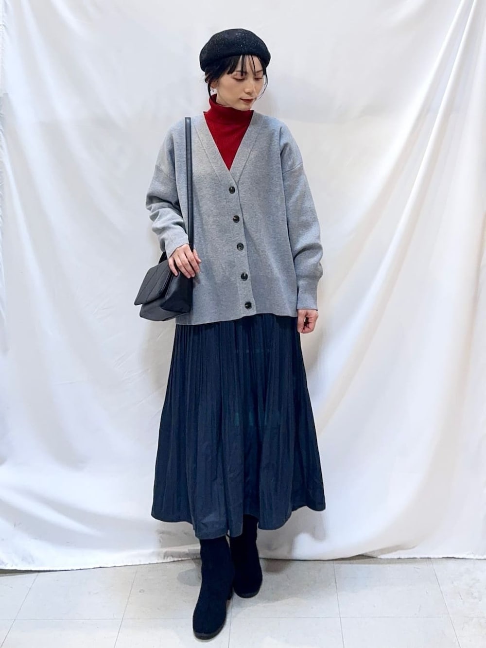 Woman in an oversized cardigan with a turtleneck and a pleated skirt