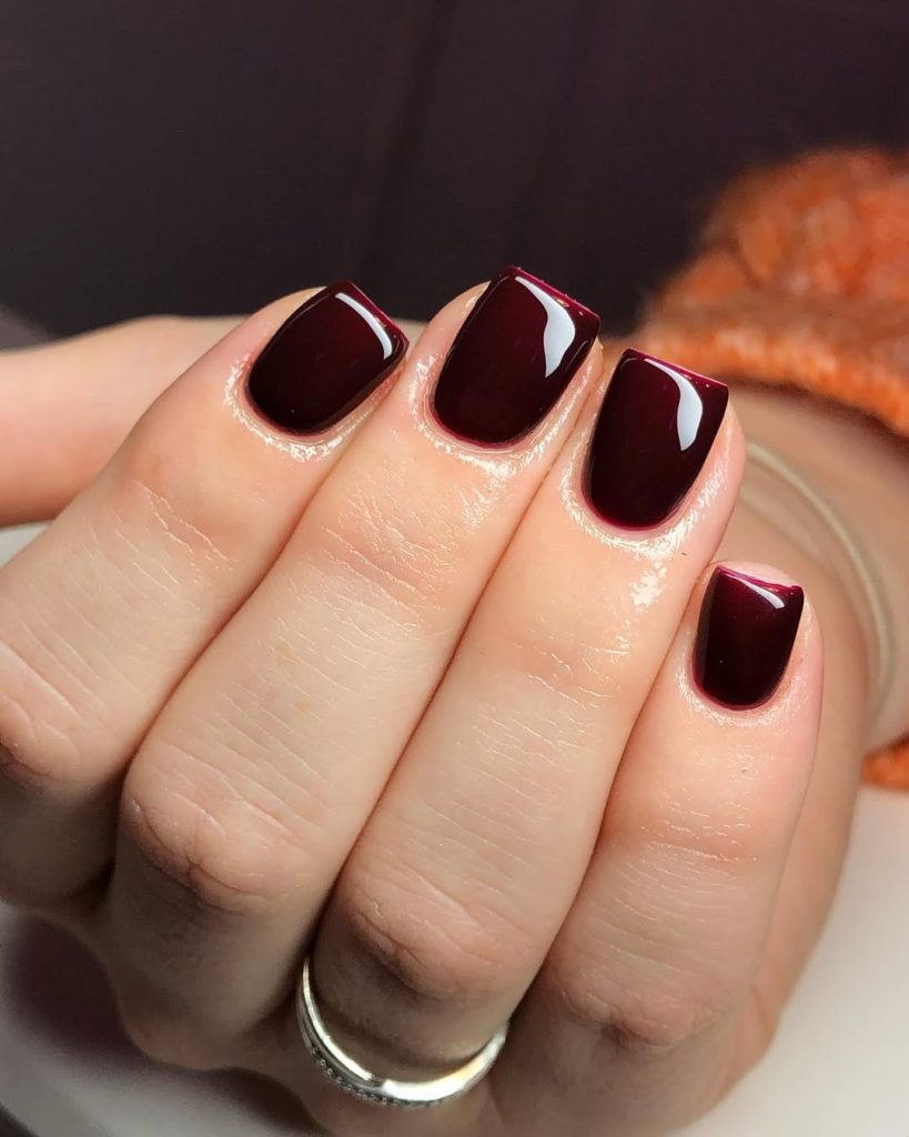 Short glossy cherry-red nails in a rich, juicy crème finish.
