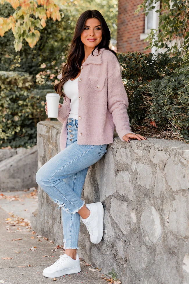 Woman wearing a fuzzy blush-pink cardigan with light-wash distressed jeans and white sneakers