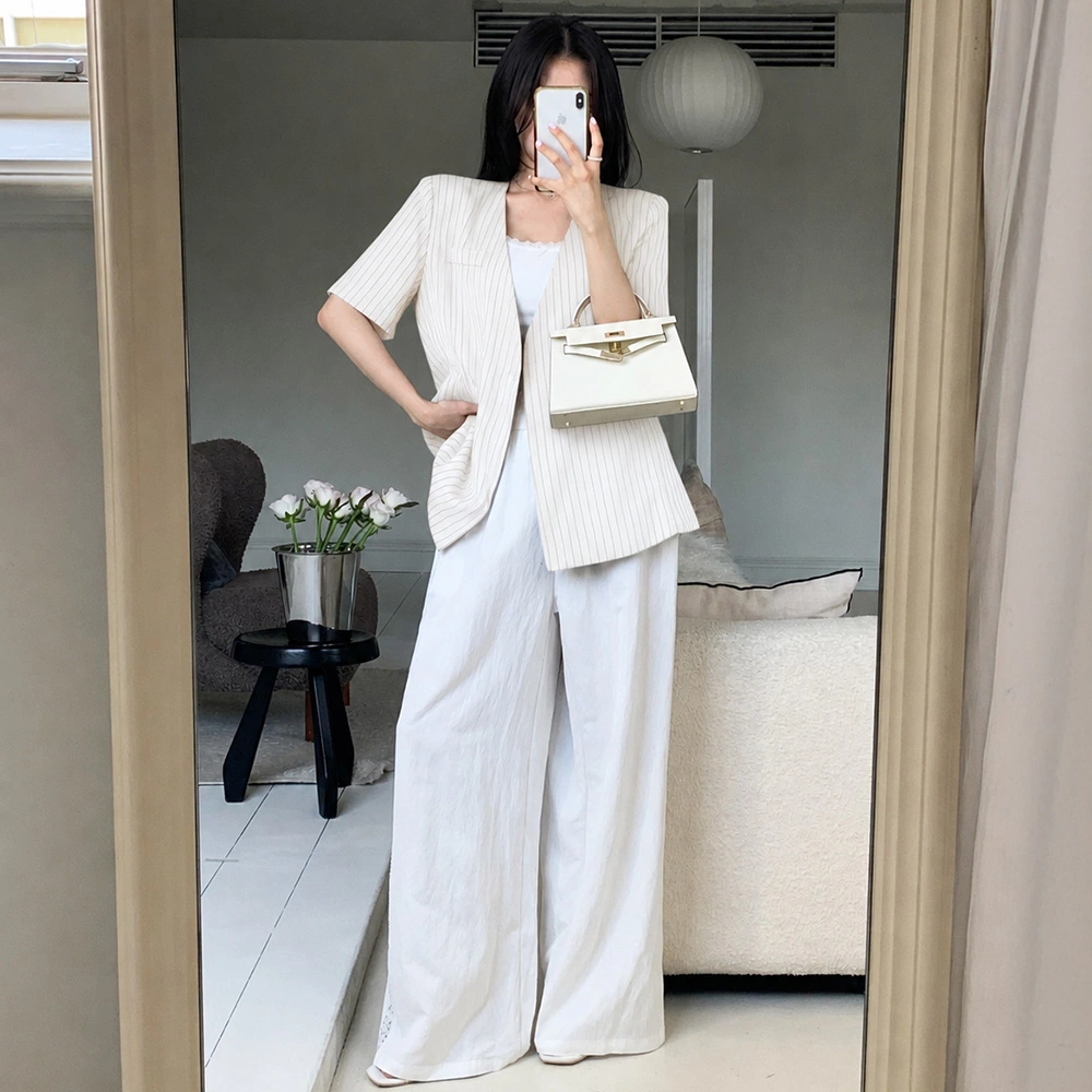 White pinstripe short-sleeve blazer with wide-leg white pants and a structured white mini bag