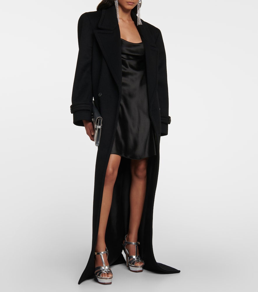Woman in a floor-length black coat over a black satin slip dress with silver heels