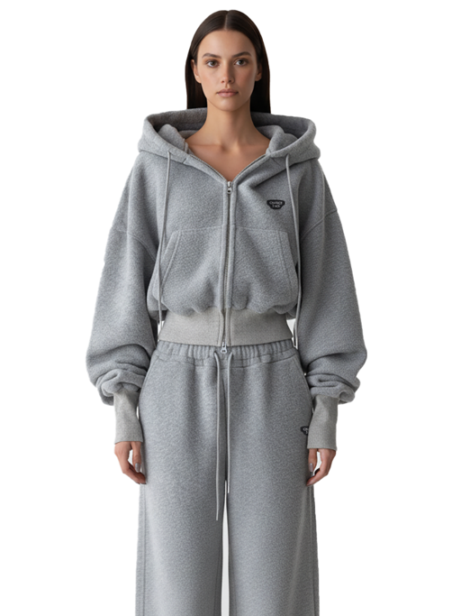 Woman wearing a heather grey zip-up hoodie with the hood up and matching wide-leg grey sweatpants