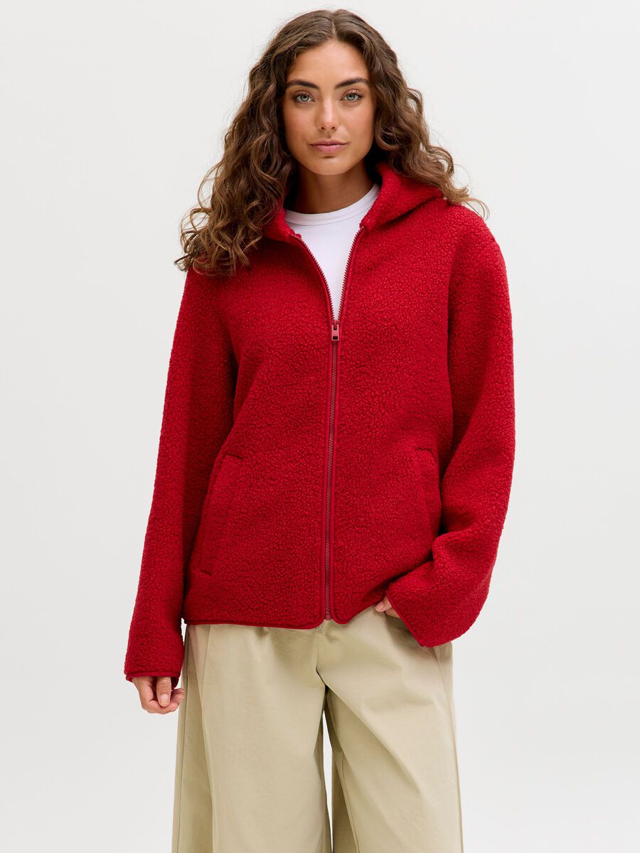 Woman in a red fleece jacket with a white tee and beige trousers