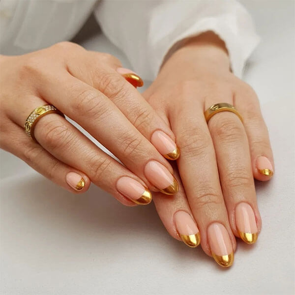 Short nails with a nude base and metallic gold chrome french tips