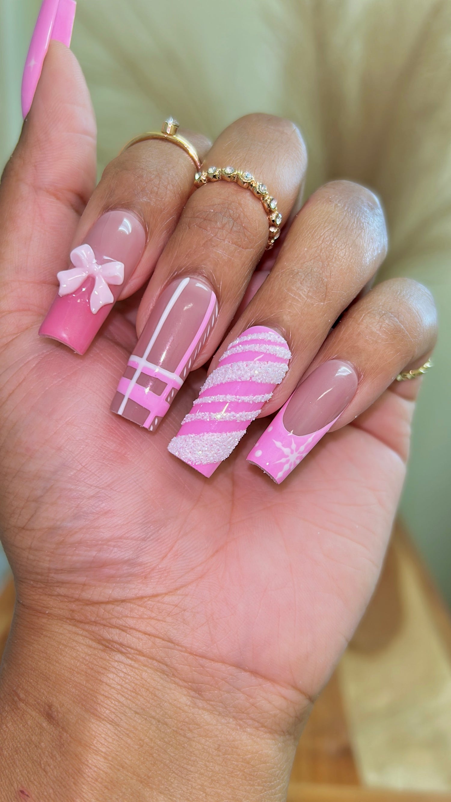 Long square pink nails with a 3D pink bow, plaid pattern, sugar glitter stripes and snowflake art