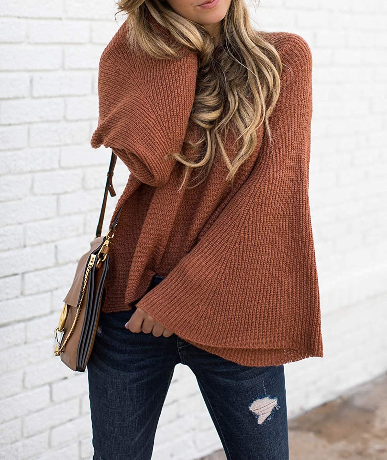 Rust bell-sleeve oversized knit sweater with dark distressed skinny jeans and a tan crossbody bag