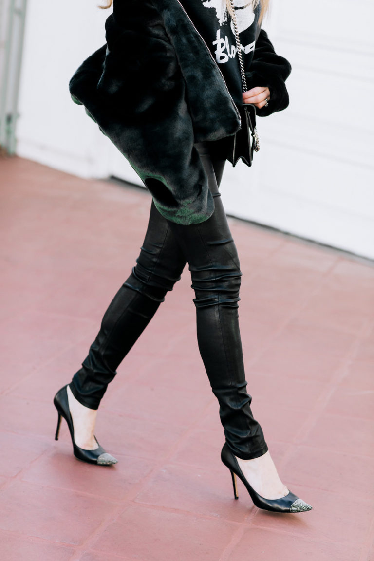 Woman in black faux fur jacket with leather pants and pointed heels