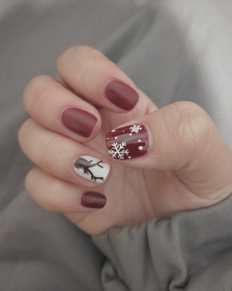 Short matte cranberry Christmas nails with white snowflake art and a white accent nail
