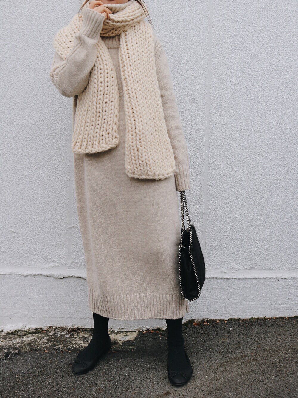 Beige knit midi sweater dress with a chunky cream knit scarf, black tights, ballet flats and a black chain-strap shoulder bag