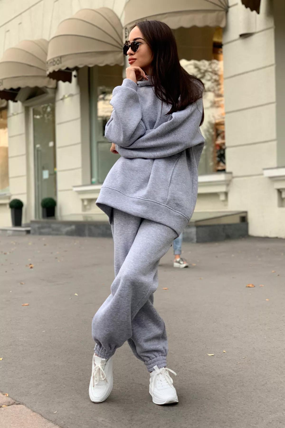 Woman wearing a gray matching hoodie and jogger set with white sneakers on a city street