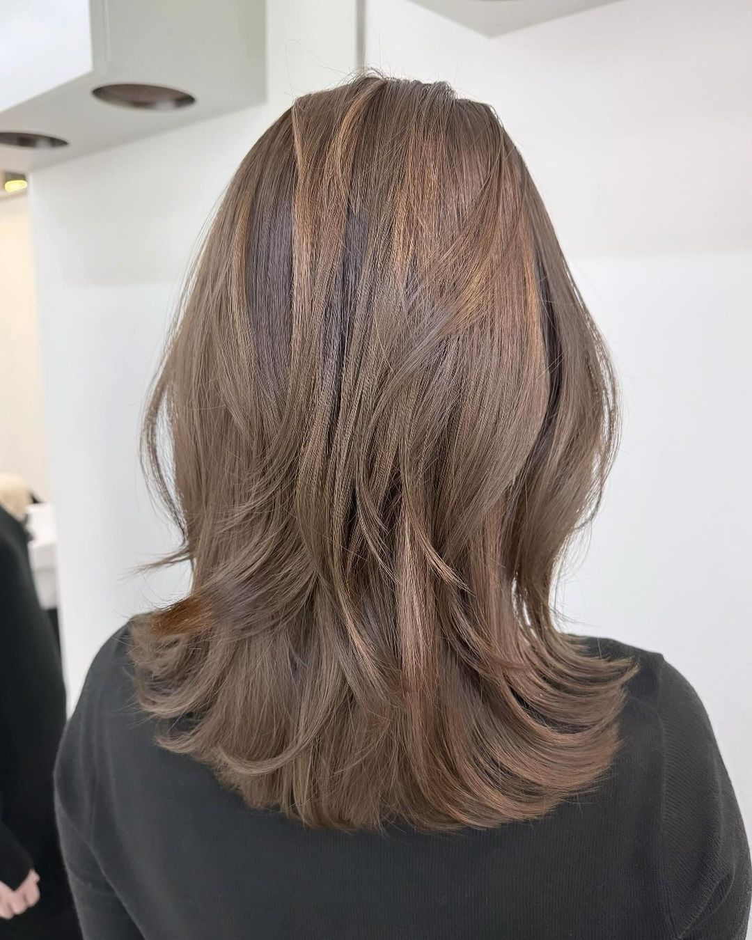 Back view of ash brown mid-length layered hair with feathered ends