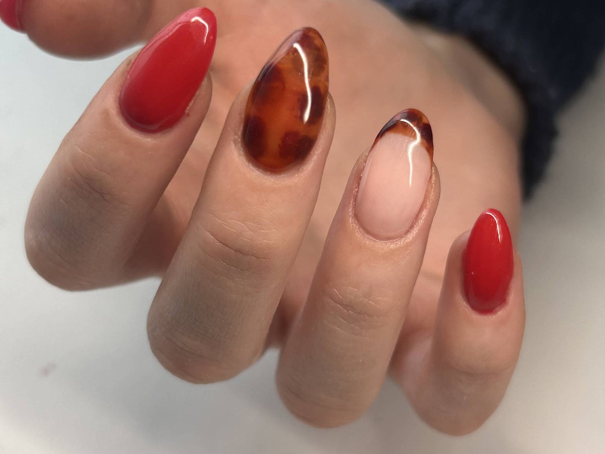 Almond nails mixing solid cherry red with amber tortoiseshell accents