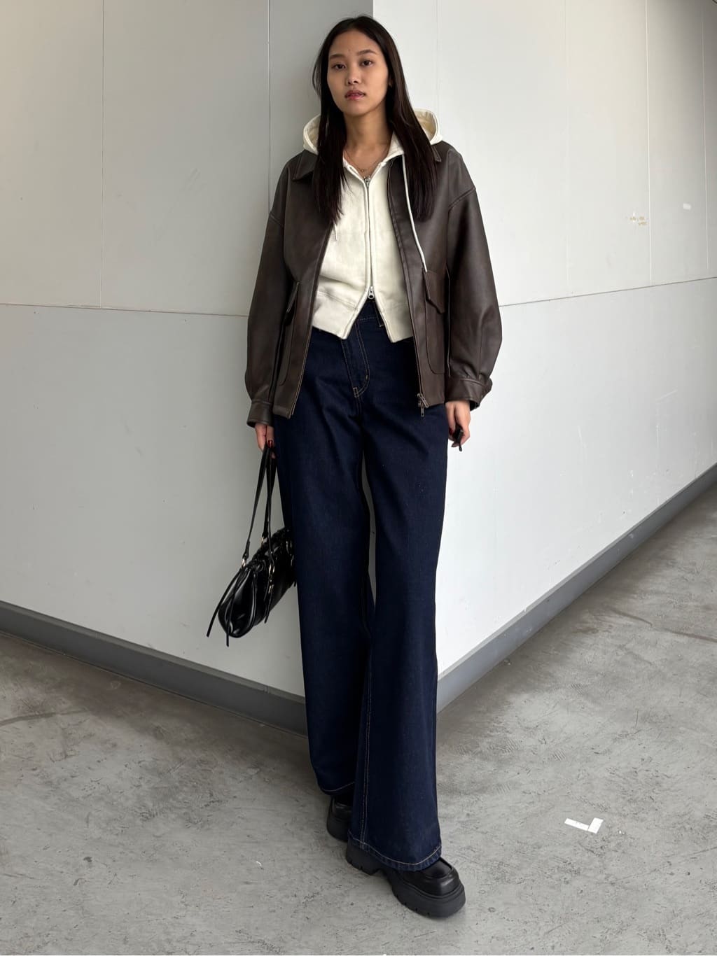 Faux leather jacket with a cream hoodie and wide-leg jeans