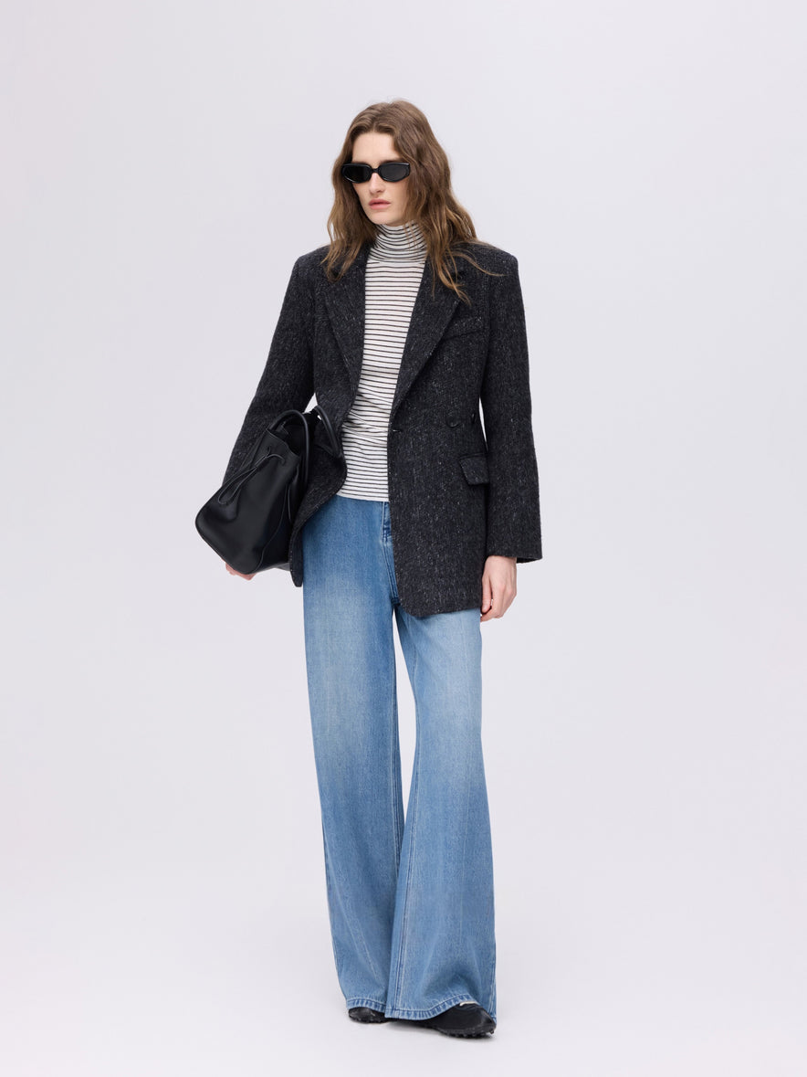 Woman in a charcoal tweed blazer over a striped turtleneck with light-wash wide-leg jeans