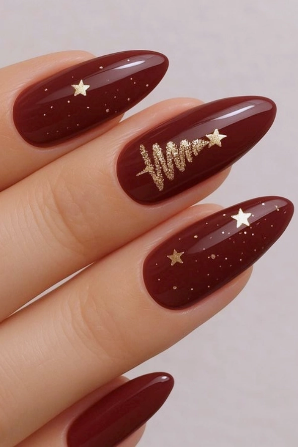 Deep wine-burgundy almond nails with a gold glitter Christmas tree and stars