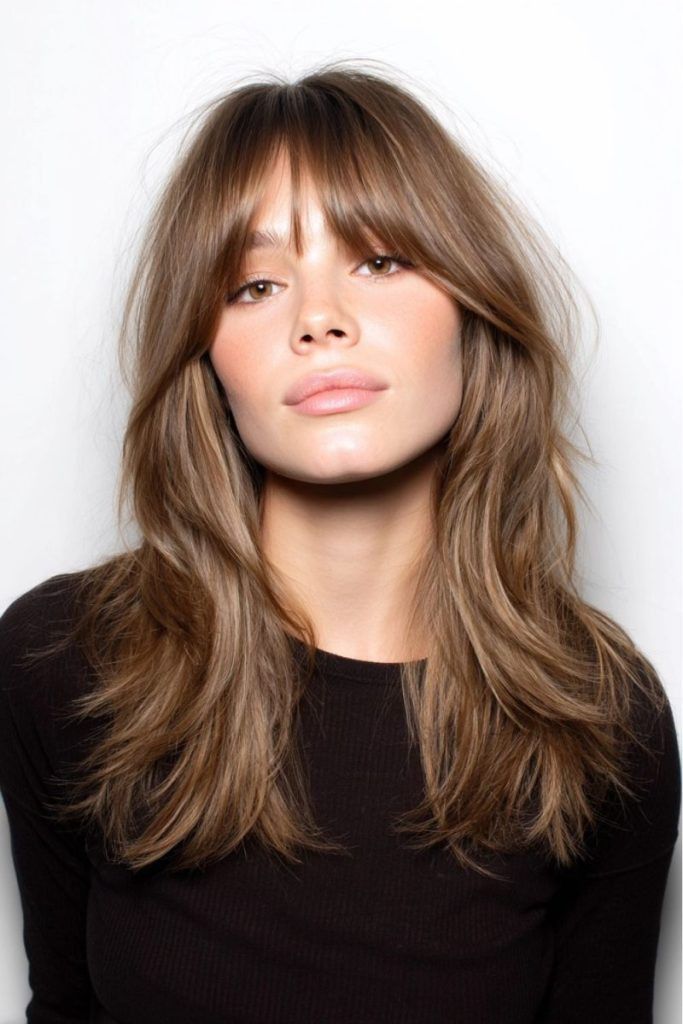 Woman with long caramel layered hair and curtain bangs