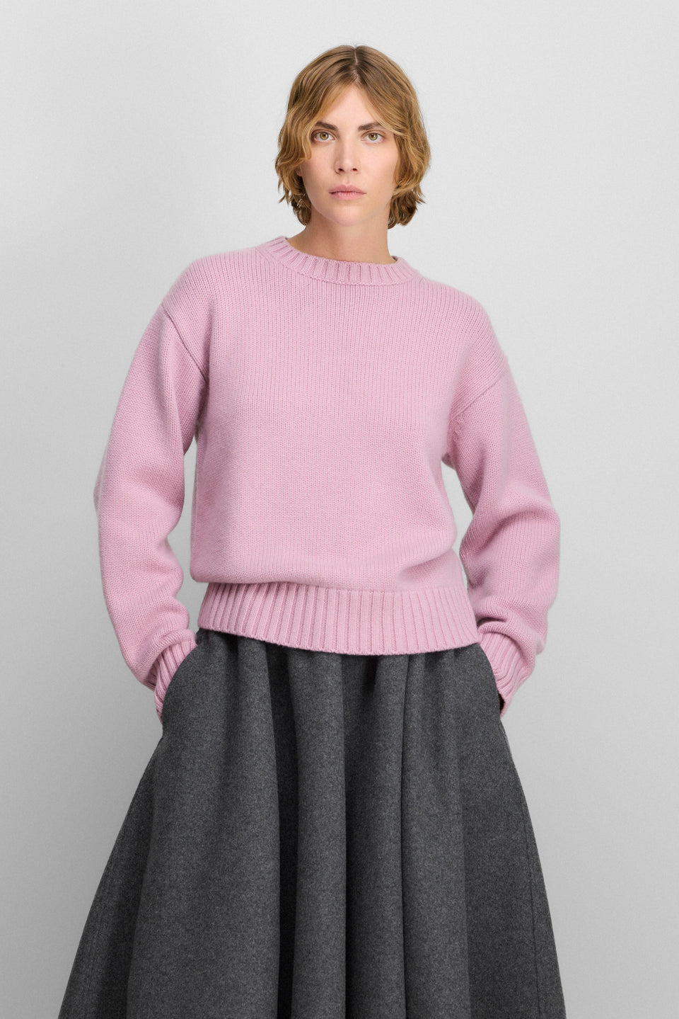 Mature woman in a blush-pink cashmere sweater with a gray wool midi skirt