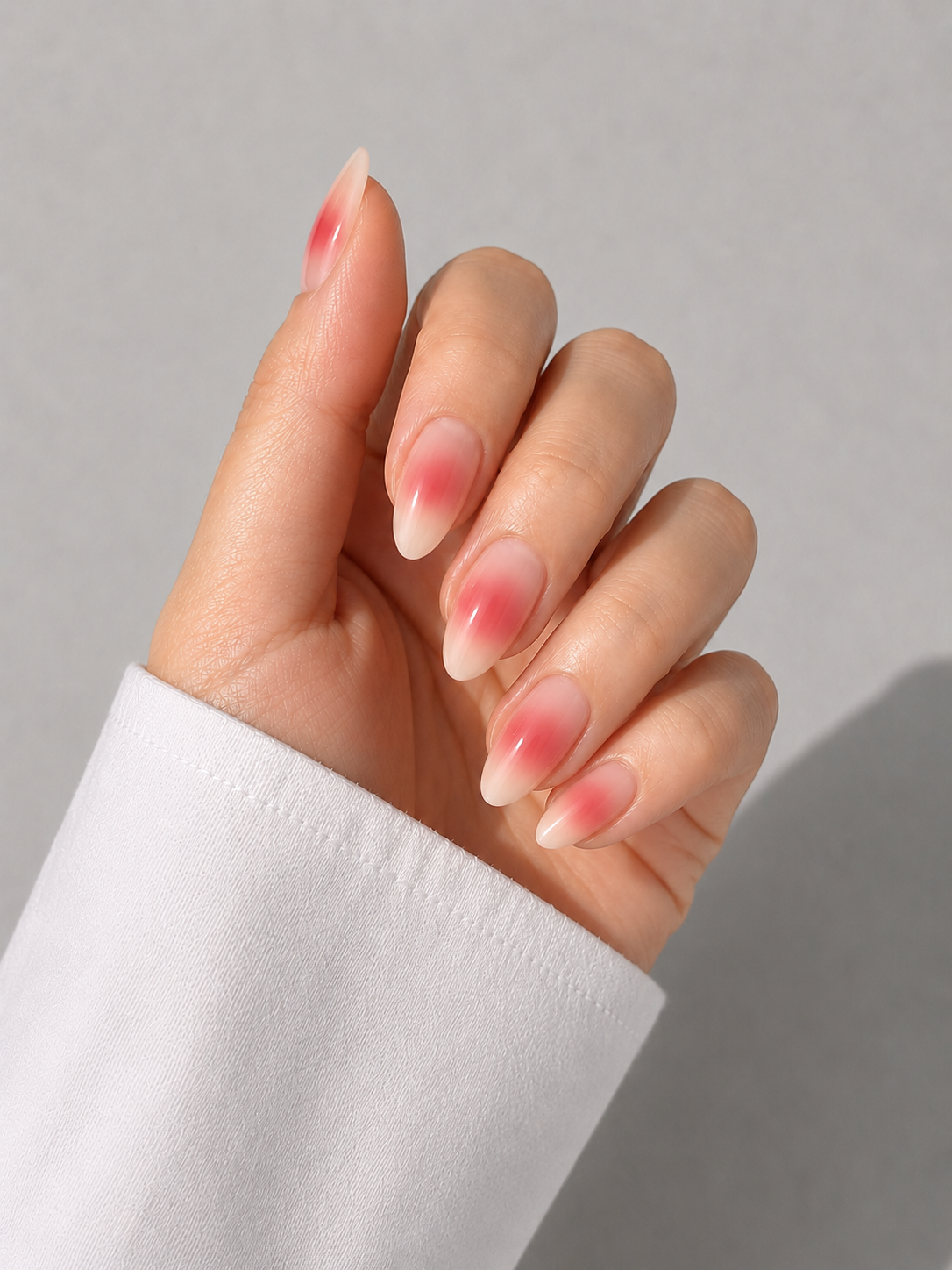 Almond nails with a soft cherry red aura blush over a milky base