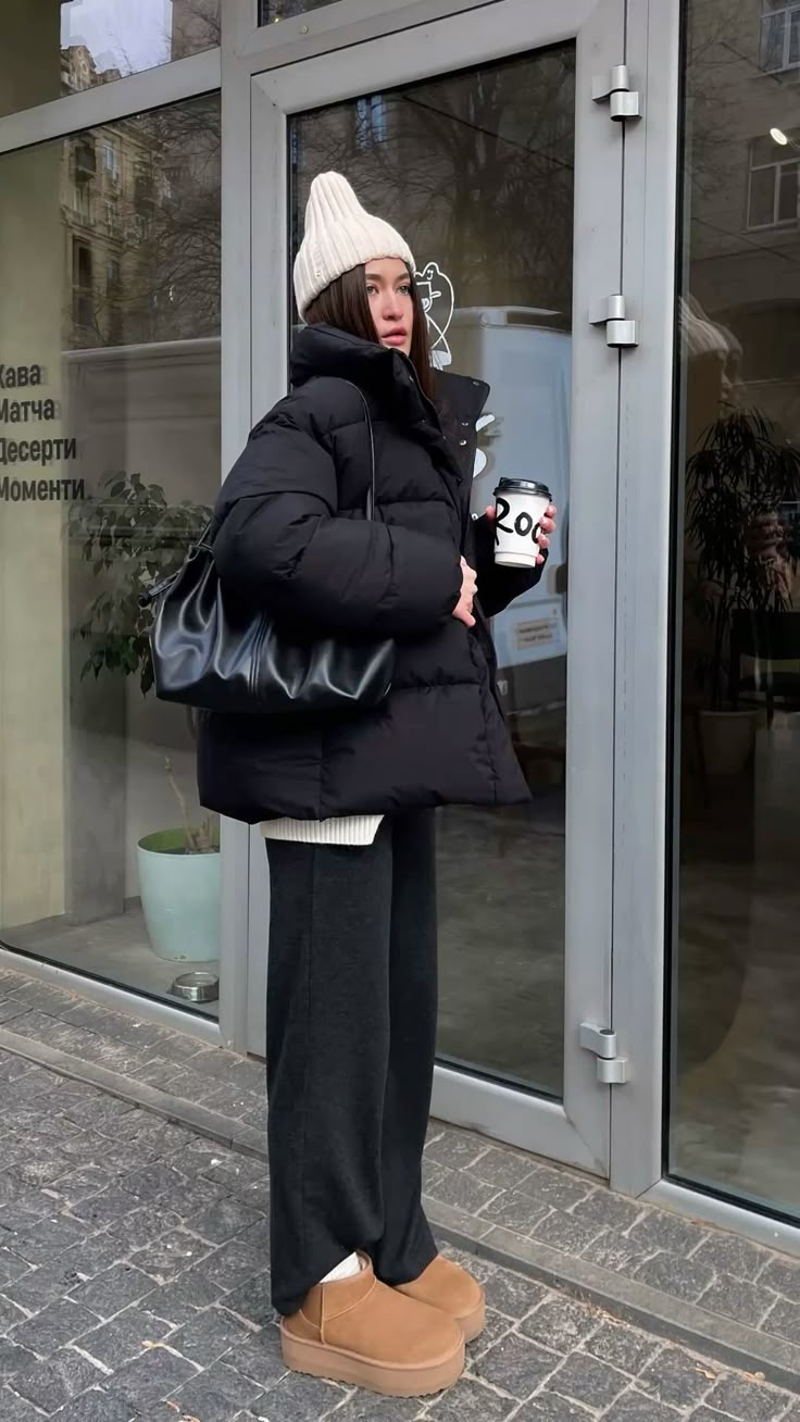 Woman in a black puffer jacket and wide-leg sweatpants wearing chestnut platform ugg boots and a white beanie
