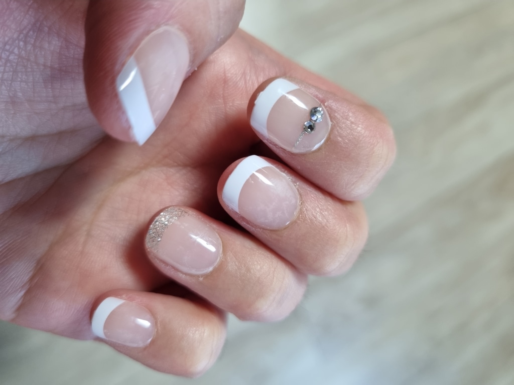 Classic white French tips on short round nails with a silver glitter accent nail.