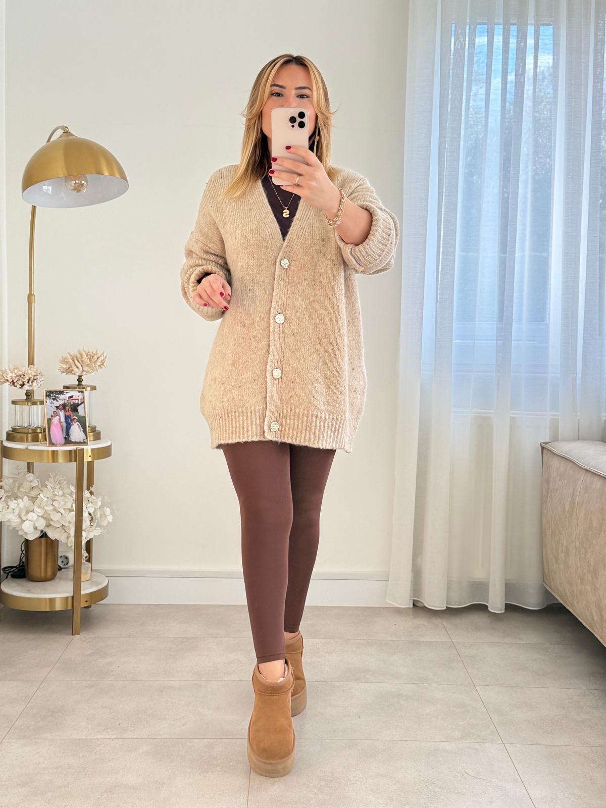 Woman in an oversized beige buttoned cardigan, brown leggings and tan suede boots