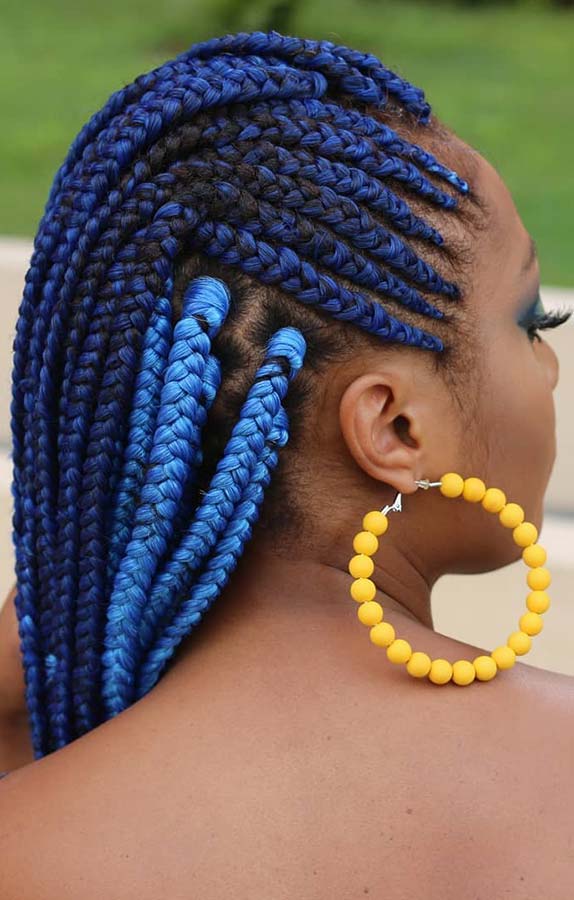 Cobalt blue box braids on a Black woman with a yellow beaded earring